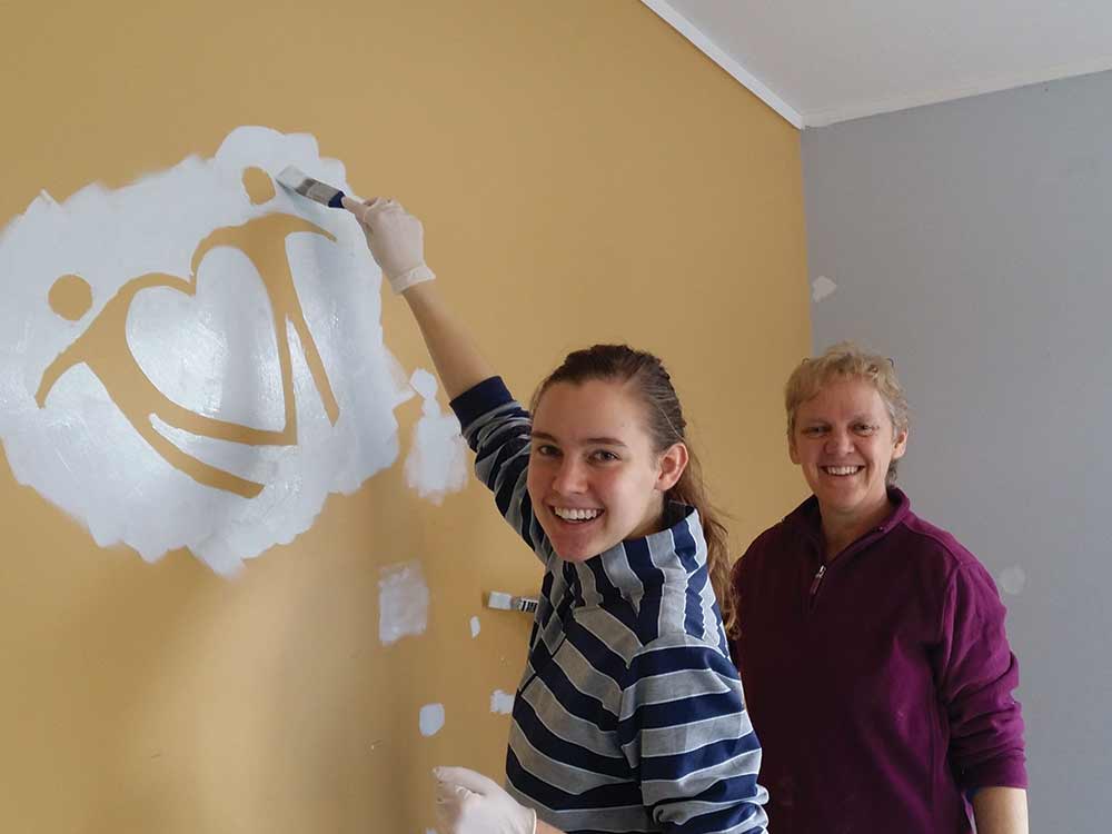painting love your neighbour logo on wall at 126 catherine lynette2